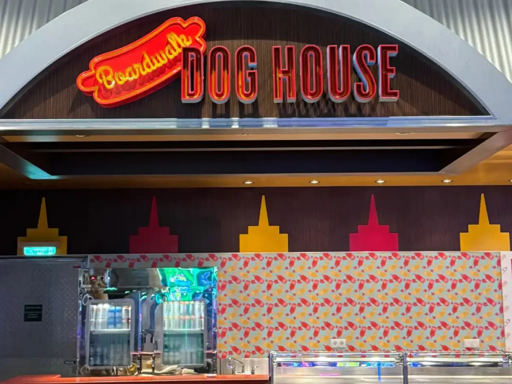 The neon sign and storefront facade of a hot dog restaurant called Doghouse.