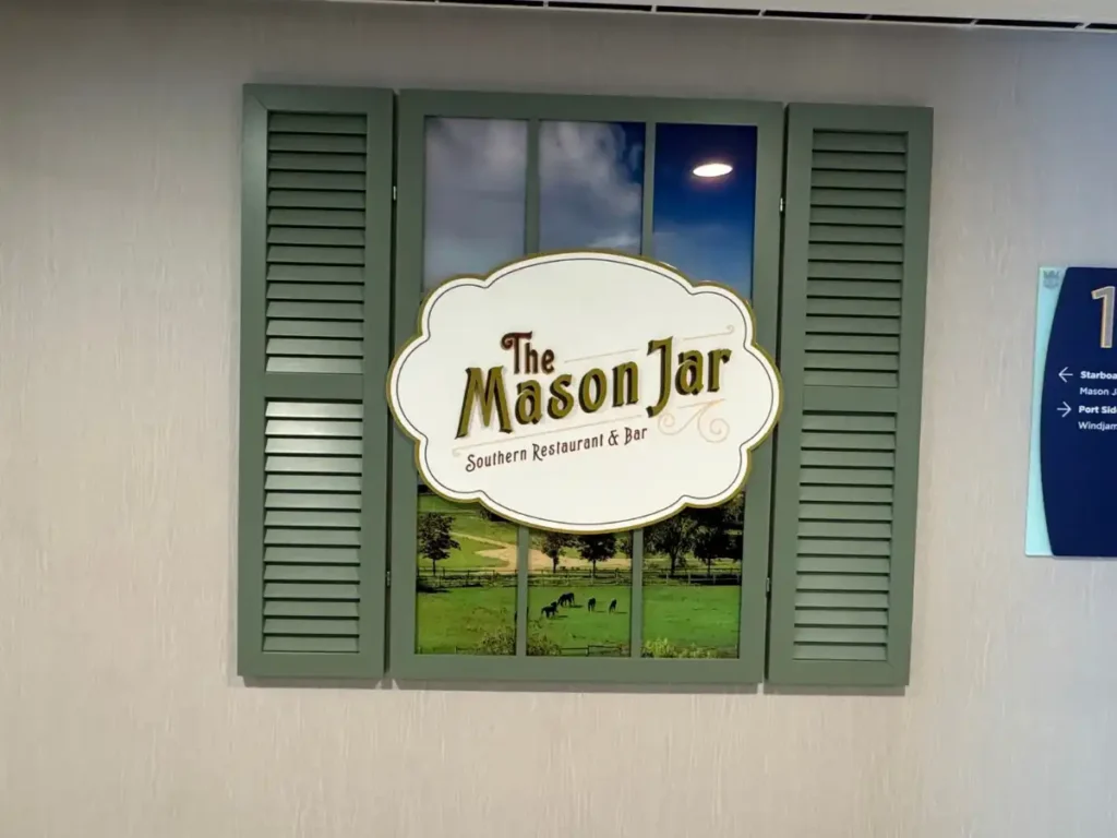 A decorative restaurant window sign for The Mason Jar featuring green shutters.