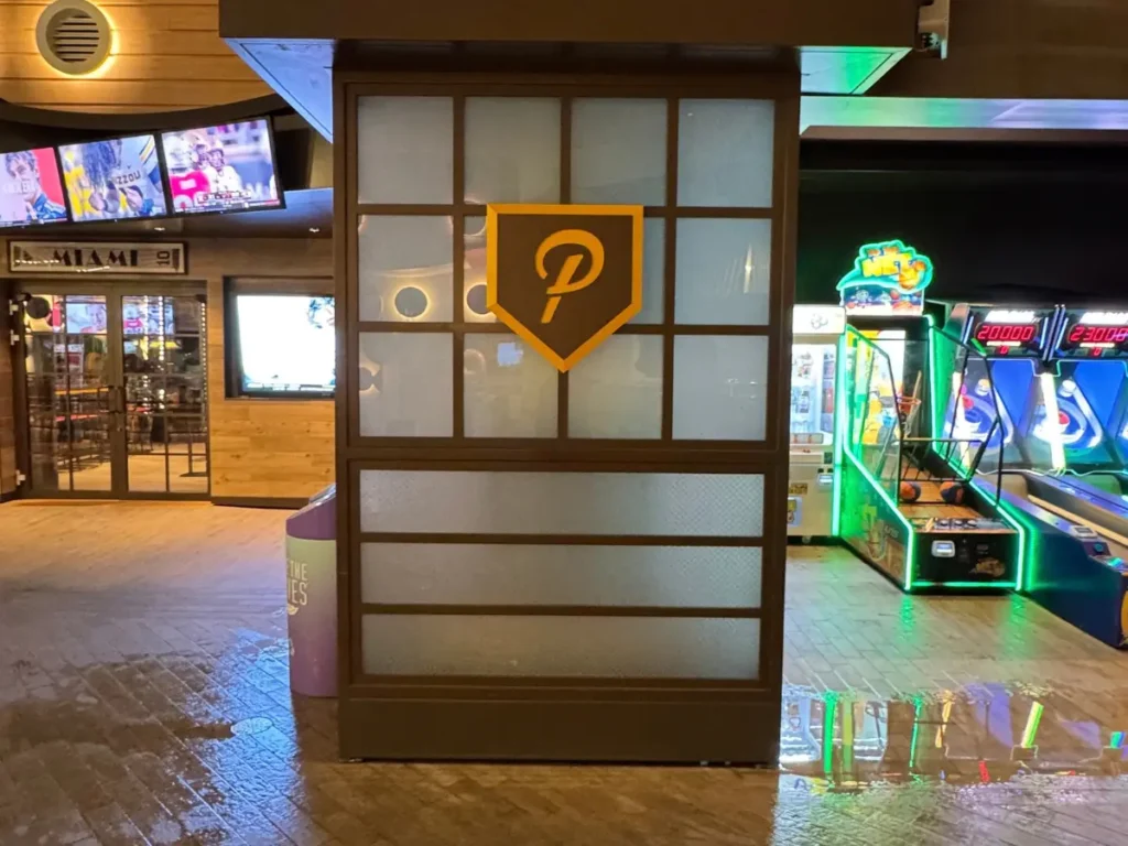 A wooden sign featuring the Playmakers logo and a crest on a restaurant wall.