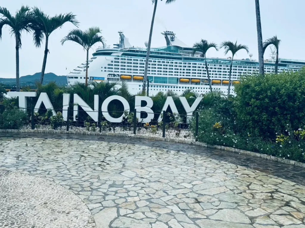 A large cruise ship (Adventure of the Seas) docked behind the Taino Bay sign at the cruise port in Puerto Plata, Dominican Republic.