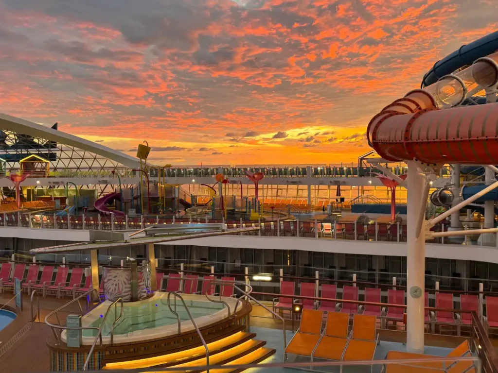 A colorful sunset viewed across a cruise ship pool deck.
