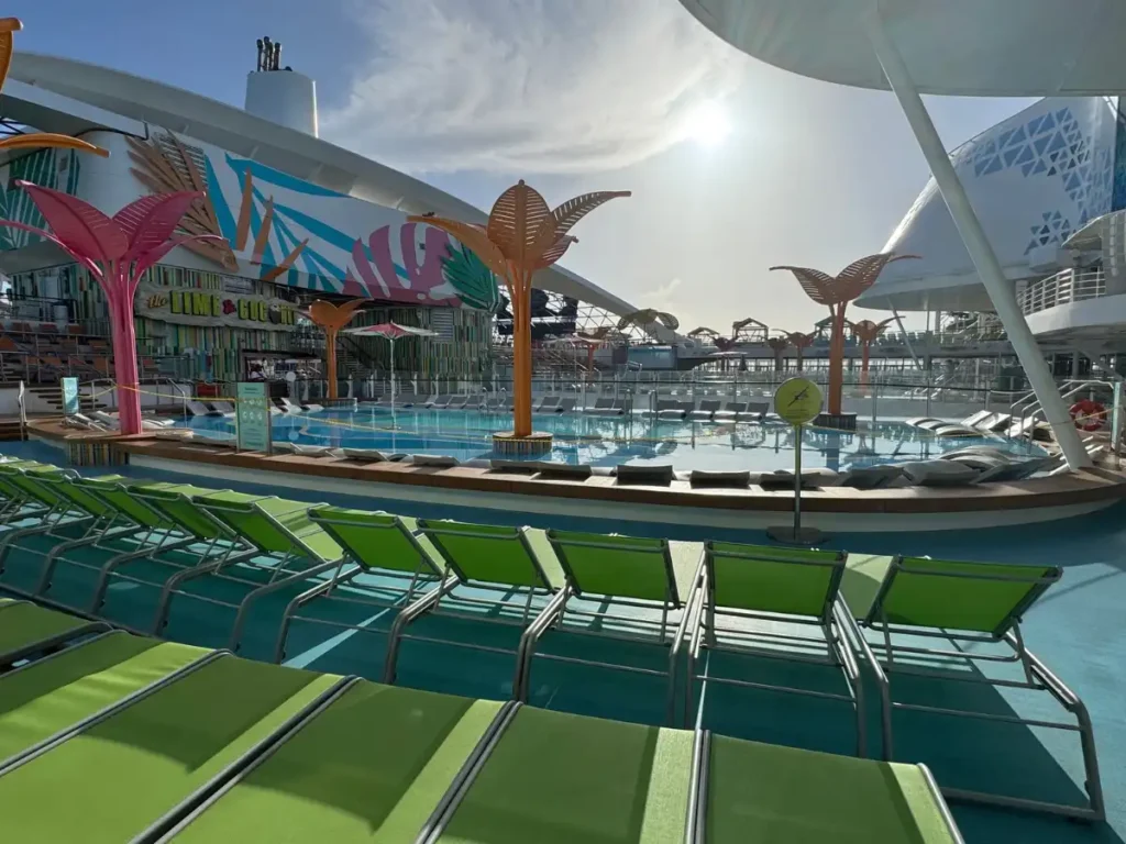 A sprawling cruise ship pool deck area with slides and lounge seating under a bright sky.