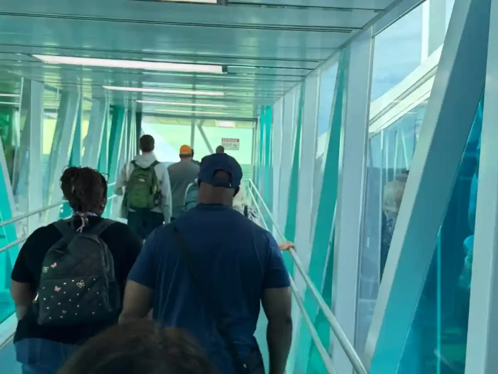 Passengers walking through the glass-paneled boarding bridge to embark on Royal Caribbean's Utopia of the Seas at Port Canaveral.
